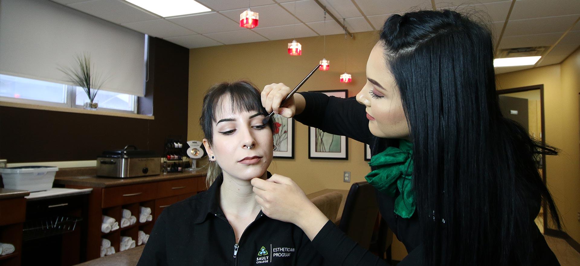 One female Esthetician student applies make-up to another Esthetician student in the ӣƵ salon spa. 