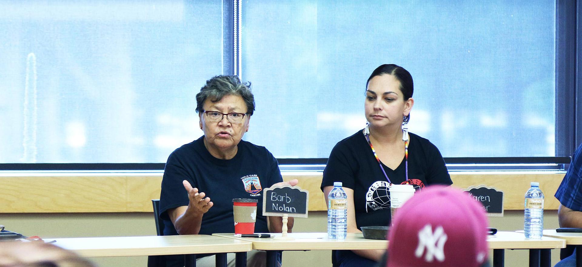 Two female ӣƵ Indigenous women conduct a group meeting with Indigenous youth.